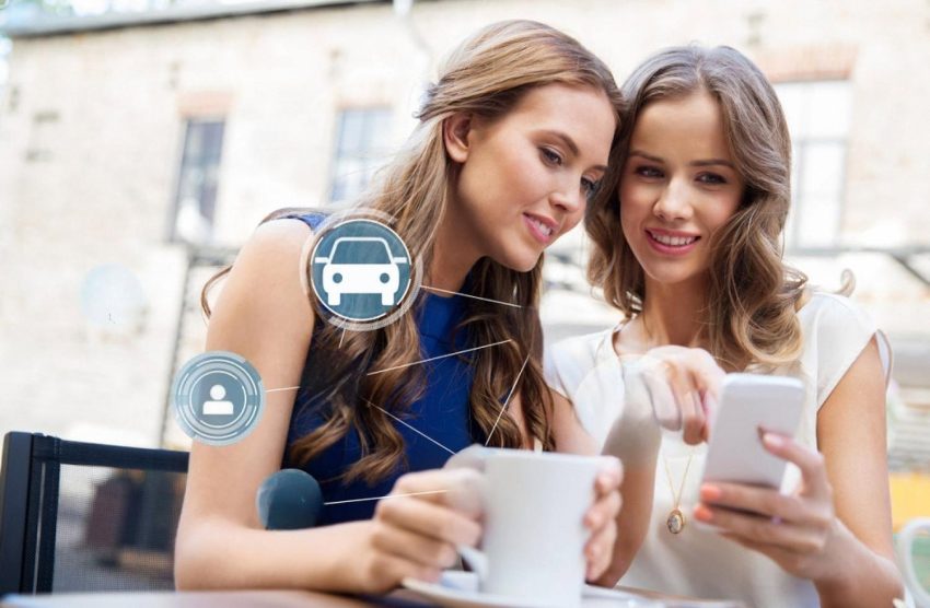 Two travellers comparing car rental offers on a smartphone at an outdoor cafe in Australia